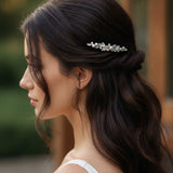 Bridal Bobby Pin with Marquise Jewels & Pearls A woman in profile with long dark brown hair wearing a delicate silver bridal hair accessory with clear stones, set against a softly blurred warm-toned background.