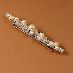 Bridal Bobby Pin with Marquise Jewels & Pearls A silver hair claw clip embellished with faux pearls and clear rhinestones, displayed diagonally on a textured brown background.