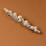 Bridal Bobby Pin with Marquise Jewels & Pearls A silver hair claw clip embellished with faux pearls and clear rhinestones, displayed diagonally on a textured brown background.