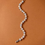 Pearl Bracelet Alternating CZ Stones A curved tennis bracelet featuring cream-colored pearls and clear round-cut gemstones in silver-toned settings, displayed on a textured brown background.