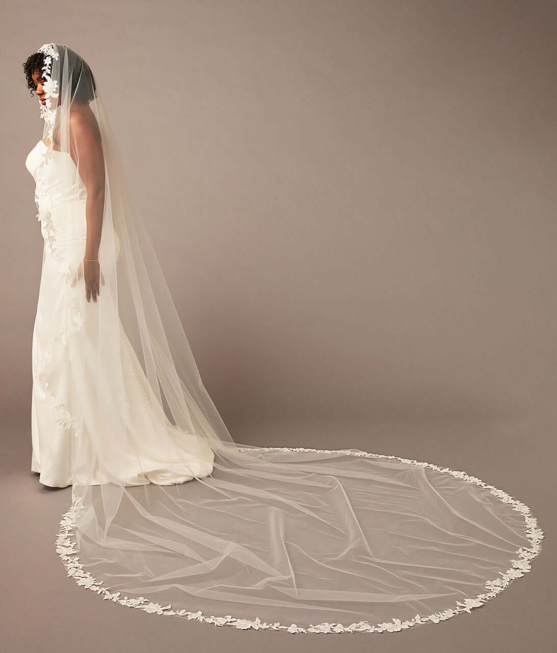 Mantilla Bridal Veil with Sequined Lace Woman wearing a long white wedding veil against a plain background
