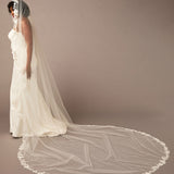 Mantilla Bridal Veil with Sequined Lace Woman wearing a long white wedding veil against a plain background
