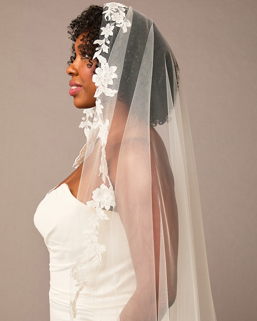 Mantilla Bridal Veil with Sequined Lace Woman wearing a white wedding dress with a floral veil against a plain background