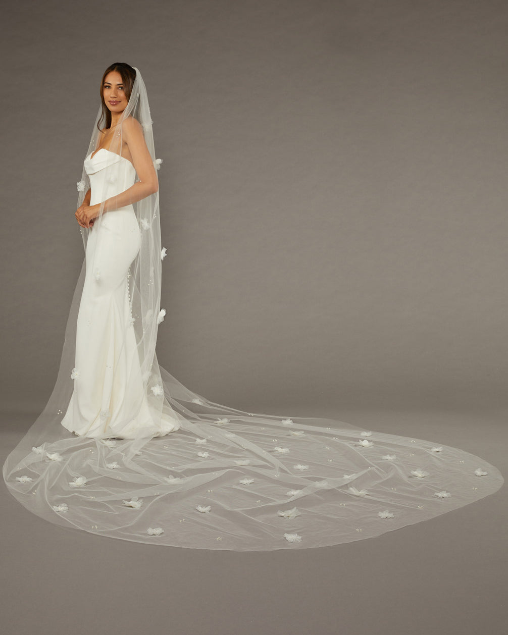 Regal Length Wedding Veil with 3D Organza Flowers Bride wearing a long, elegant wedding veil against a plain background