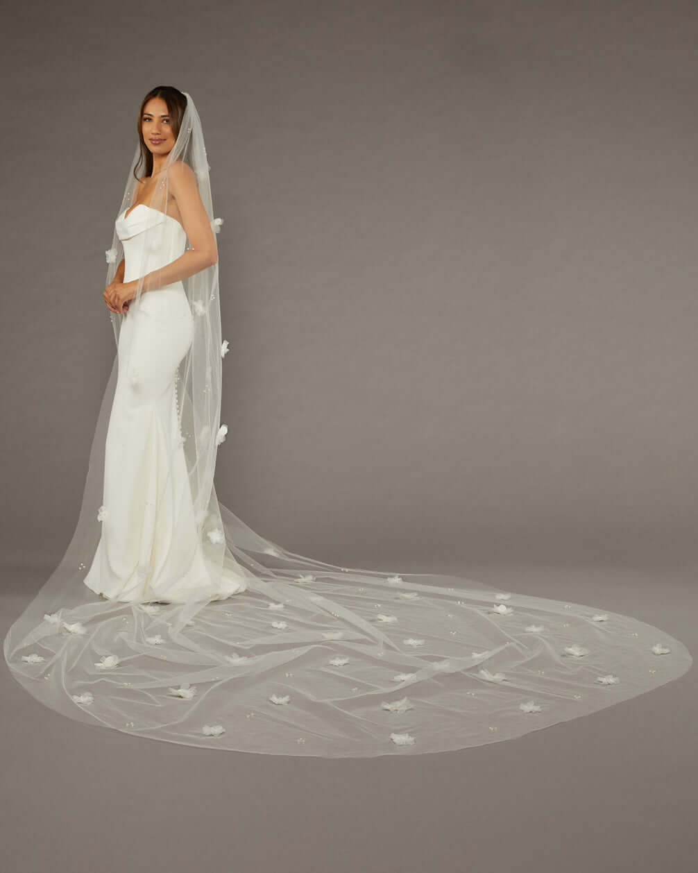 Regal Length Wedding Veil with 3D Organza Flowers Bride wearing a long, elegant wedding veil against a plain background