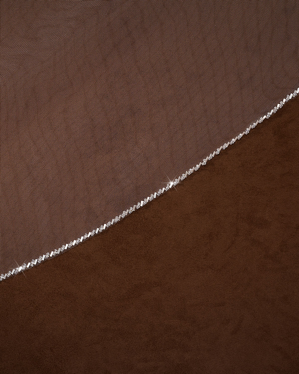Wedding Veil with Crystal and Opaque Bead Trim A close-up of a brown textured fabric with a delicate silver beaded chain running diagonally across it.