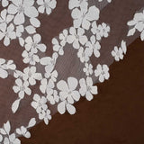 Light ivory floral lace trim with embroidered cherry blossom motifs over a sheer brown mesh, shown laid diagonally on a dark brown surface.
