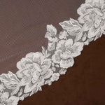 Wide Mantilla Cathedral Veil with Floral Lace Cassandra Lynne -floral lace trim with embroidered roses and leaves laid diagonally across a dark brown textured fabric background.