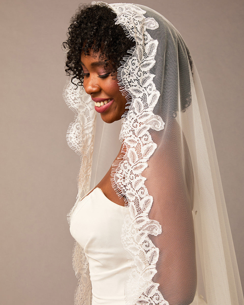 Luxe Tulle Lace Mantilla Fingertip Bridal Veil Woman wearing a white lace veil against a plain background