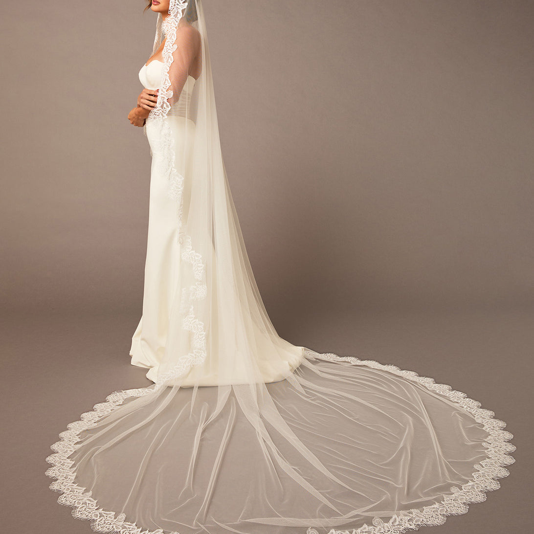 Woman wearing a white wedding dress with a long veil against a brown background Luxe Tulle Lace Mantilla Cathedral Bridal Veil