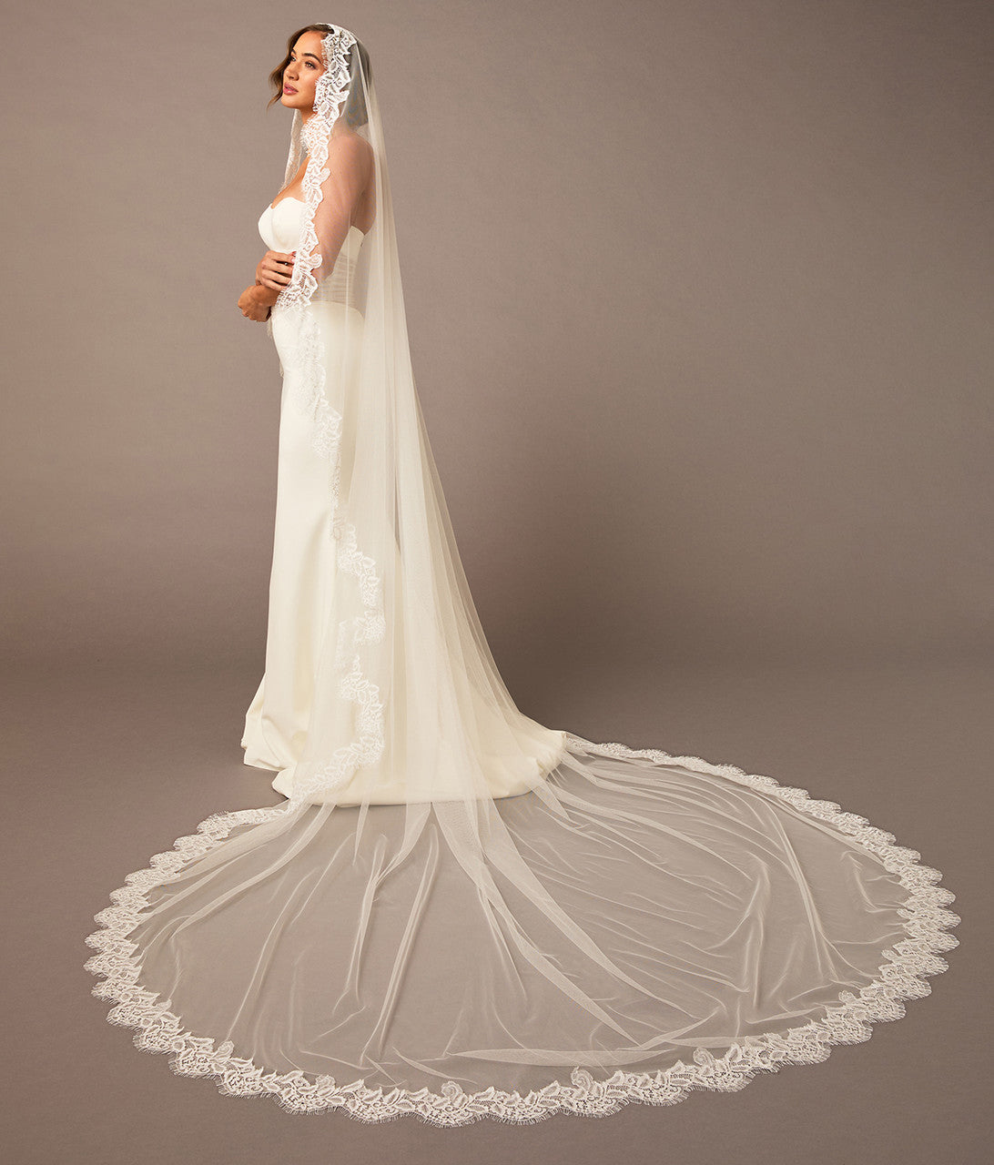 Woman wearing a white wedding dress with a long veil against a brown background Luxe Tulle Lace Mantilla Cathedral Bridal Veil