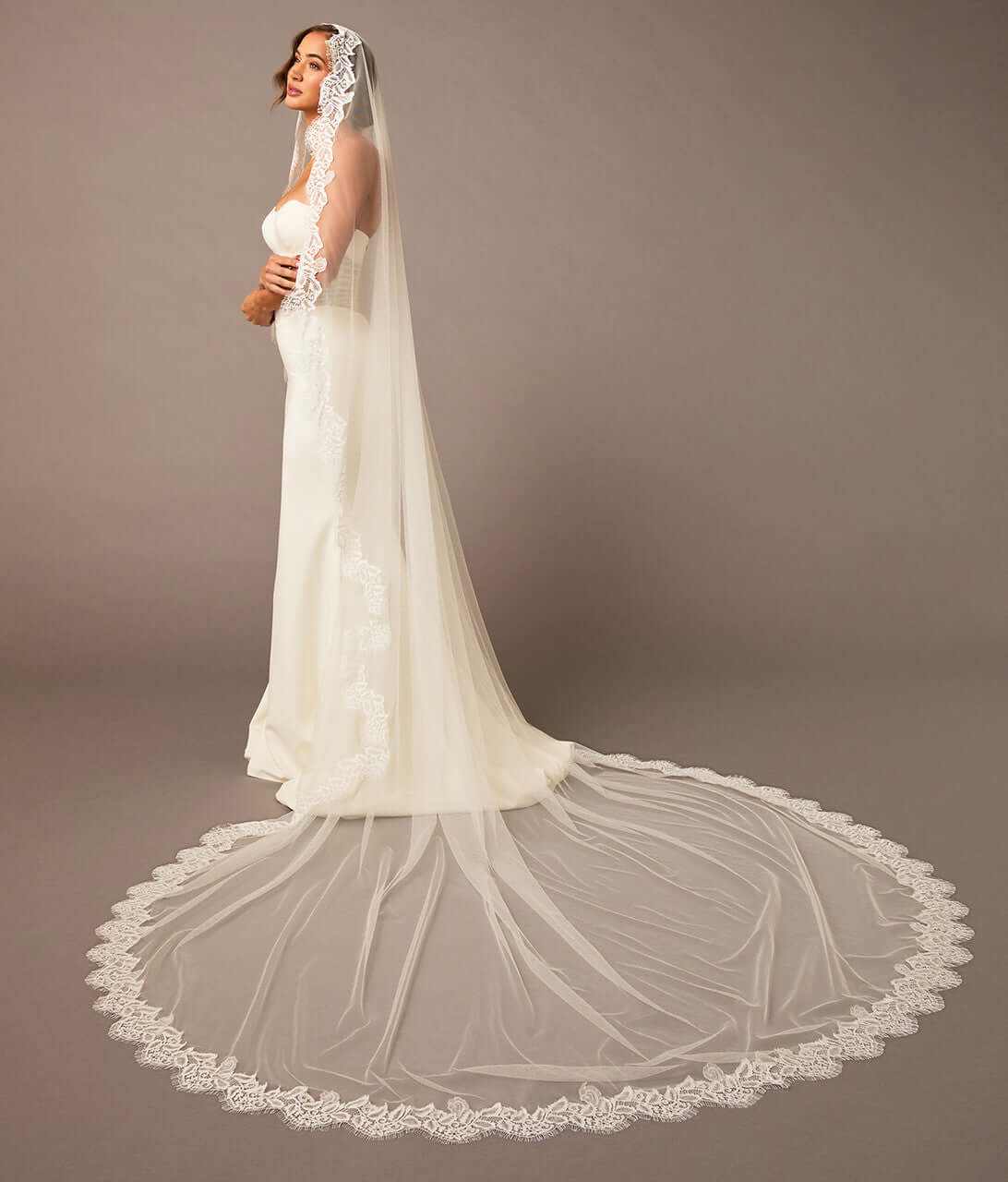 Woman wearing a white wedding dress with a long veil against a brown background Luxe Tulle Lace Mantilla Cathedral Bridal Veil