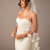 Woman wearing a white wedding dress with a floral veil against a brown background