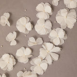 White flowers with pearl centers scattered on a beige background