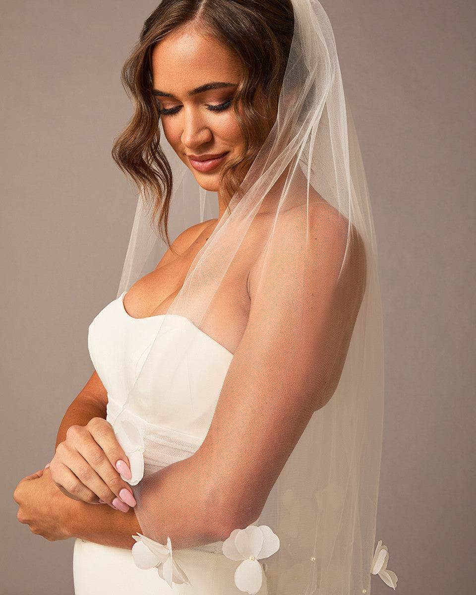 Woman wearing a white wedding dress with a veil against a neutral background