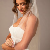 Woman wearing a white wedding dress with a veil against a neutral background