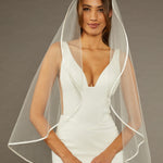 Simple Satin Trim Fingertip Bridal Veil Woman wearing a wedding dress with a veil against a brown background