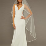 Waltz Waterfall Veil with Satin Ribbon Trim Woman wearing a wedding dress with a long veil against a brown background
