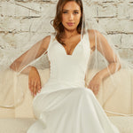 Waltz Waterfall Veil with Satin Ribbon Trim Woman in a wedding dress with a veil sitting on a couch against a textured wall.