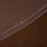 Bridal Veil with Double Crystal Trim Cassandra Lynne A close-up of a brown sheer mesh fabric with a delicate diagonal line of small clear rhinestones or beads along one edge.